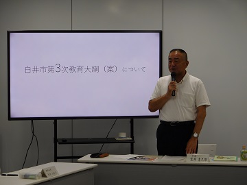 白井市第3次教育大綱(案)について説明をする様子