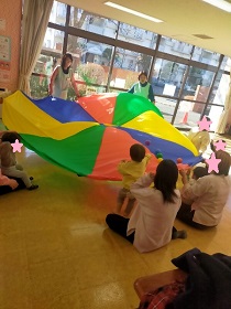 パラバルーンにボールを投げるこども