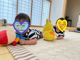 床でうつぶせになる双子の赤ちゃんの写真